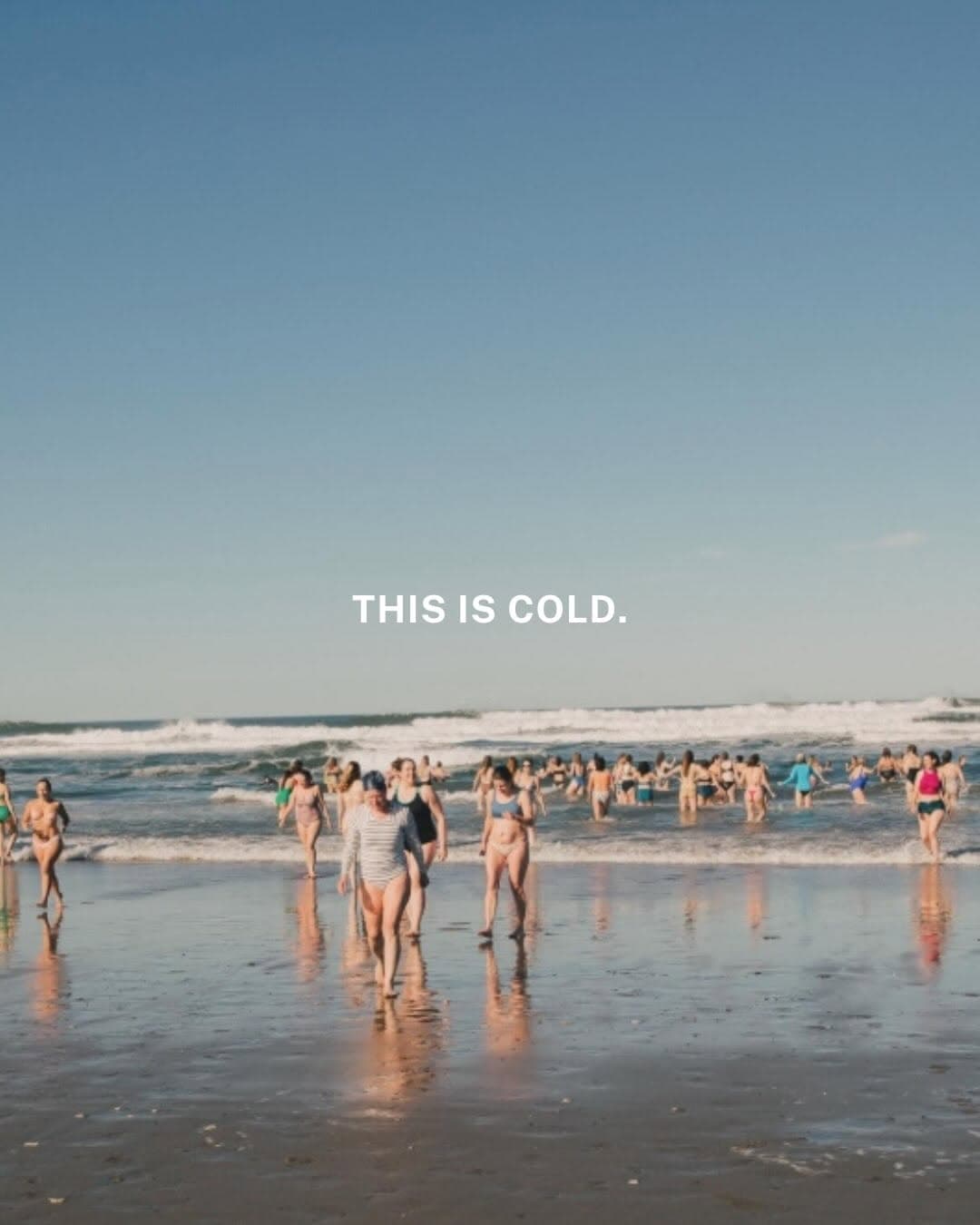 Large group of women gathered on Ocean Beach in San Francisco for International Women's Day cold plunge event with Ocean Beach Plunge Club